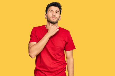 Genç, yakışıklı bir adam gündelik kırmızı tişört giyiyor. Ağrılı boyuna dokunuyor. Grip, mantar ve enfeksiyon yüzünden boğaz ağrısı çekiyor. 