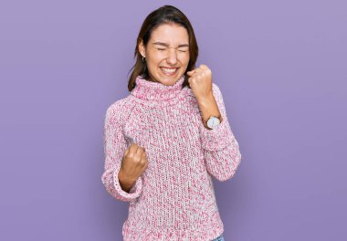 Kışlık yün kazak giyen genç beyaz kız kolları havada ve gözleri kapalı bir şekilde başarıyı kutluyor ve şaşırıyor. Kazanan konsept. 