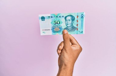 İspanyol el, 50 Yuan 'lık Çin banknotunu soyutlanmış pembe arka planda tutuyor..