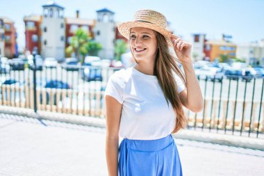 Genç sarışın kadın tatilde gülümsüyor. Mutlu bir şekilde caddede yürüyor.