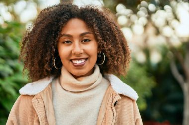 Genç Afrikalı Amerikalı kadın parkta mutlu bir şekilde gülümsüyor..