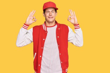 Beyzbol üniforması giyen yakışıklı beyaz adam rahatla ve gözleri kapalı gülümse parmaklarıyla meditasyon hareketi yapıyor. yoga konsepti. 