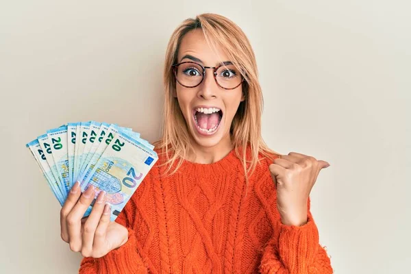 Красива Блондинка Тримає Банкноти Євро Вказуючи Великий Палець Сторону Посміхаючись — стокове фото