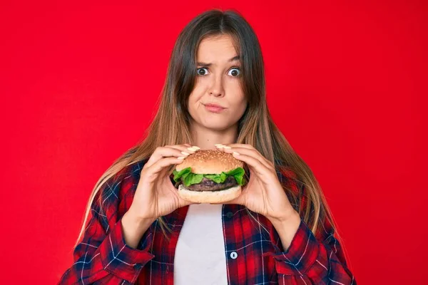 Belle Femme Caucasienne Mangeant Burger Classique Savoureux Sceptique Nerveux Fronçant — Photo