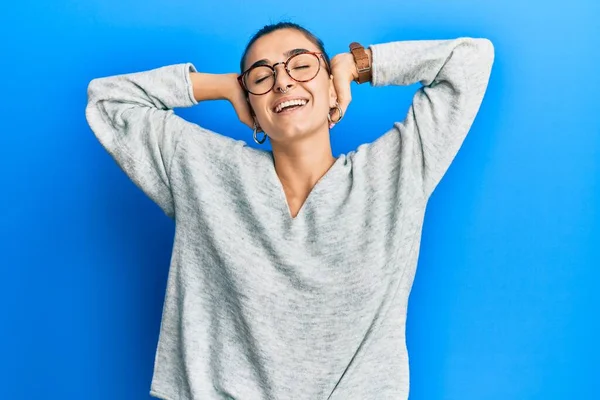 Young hispanic woman wearing casual clothes relaxing and stretching, arms and hands behind head and neck smiling happy