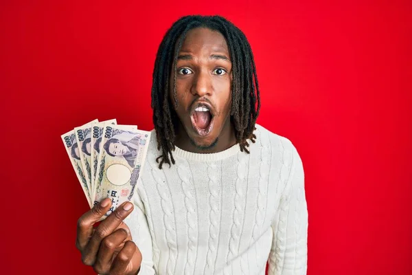 5000円の紙幣を持っているアフリカ系アメリカ人の男性は 不信の顔のために口を開けて怖がって驚いています — ストック写真