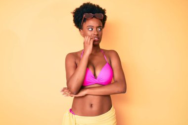 Genç Afro-Amerikan kadın bikini giyiyor stresli ve gergin görünüyor ağızları tırnak yiyen ellerle. anksiyete. 