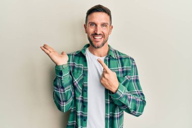 Sakallı, sıradan giyinen yakışıklı adam kameraya hayret ediyor ve gülümsüyor.. 