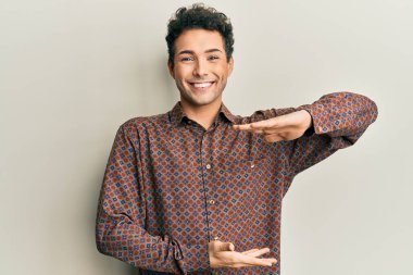 Yakışıklı, sıradan kıyafetler giyen, elleri büyük ve büyük boy işareti gösteren, ölçü sembolü olan bir İspanyol. Kameraya bakıp gülümsüyor. ölçüm kavramı. 