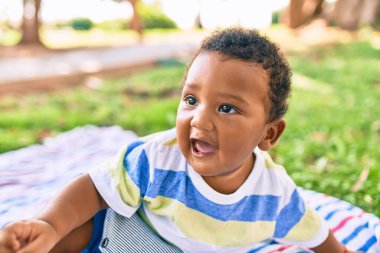Sevimli Afro-Amerikan tombul çocuk parkta çimlerin üzerinde oturuyor..