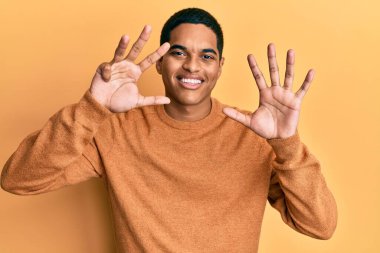 Genç, yakışıklı, sıradan bir süveter giyen, dokuz numaralı parmaklarını gösterip, gülümseyen, kendinden emin ve mutlu bir İspanyol.. 