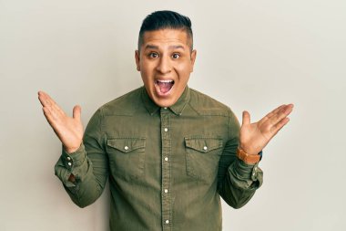 Sıradan kıyafetler giyen genç latin adam çılgın ve başarıyı kollarını kaldırıp heyecanla haykırarak kutluyor. Kazanan konsept 