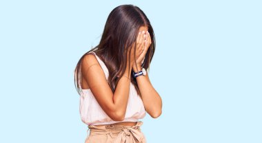 Genç İspanyol kadın gündelik kıyafetler ve ağlarken suratını ellerle kapatan üzgün yüzlü gözlük takıyor. depresyon kavramı. 