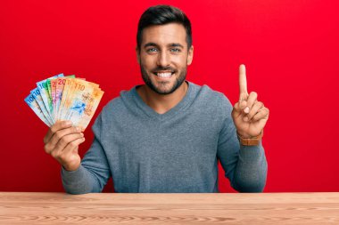 Elinde İsviçre frangı banknotları olan yakışıklı İspanyol bir adam bir fikir veya soru işareti ile gülümsüyor. 