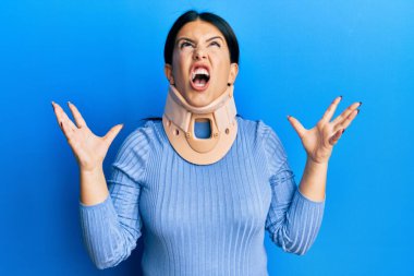 Servikal yakalı güzel esmer kadın deli gibi bağırıyor ve agresif bir ifadeyle bağırıyor ve kollarını kaldırıyor. hüsran kavramı. 