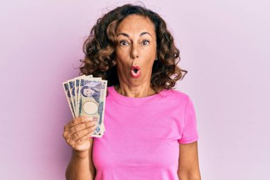 Orta yaşlı İspanyol kadın elinde Japon yeni banknotları tutuyor. Şaşırtıcı bir şekilde korkmuş ve hayrete düşmüştü. İnanmayan yüz. 