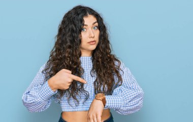 Gündelik giysiler giyen genç İspanyol kız saati, sabırsızlığı ve gecikmeyi izlemek için acele ediyor. 