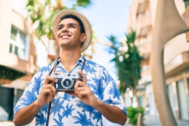 Şehrin caddesinde yürüyen klasik kamera kullanan genç Arap turist..