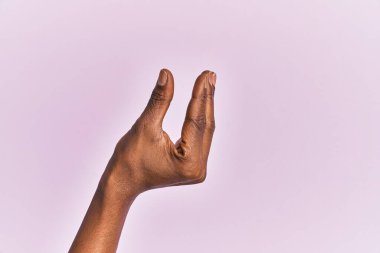 Siyah orta yaşlı bir kadının kolu ve eli pembe izole edilmiş arka plan üzerinde. Görünmez bir şeyi alıp götürüyor. Parmaklarıyla uzayı gösteren bir nesneyi tutuyor. 