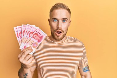 Kafkasyalı genç bir adam 100 Yuan Çin banknotları tutuyor. Şaşırtıcı bir şekilde korkmuş ve hayrete düşmüştü. 