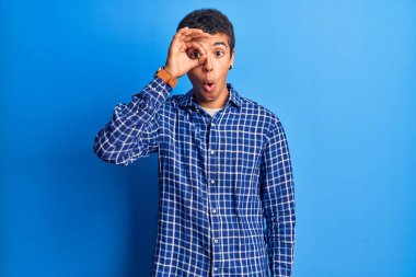 Genç Afro-Amerikalı sıradan kıyafetler giyen, şaşırmış yüzüyle şaşırmış, parmaklarından bakan bir jest yapan adam. İnançsız ifade. 