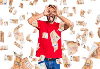 Sarışın, sakallı, sıradan kıyafetler giyen, dürbün gibi hareket eden, dilini dışarı çıkaran, parmaklarından bakan yakışıklı bir adam. çılgın ifade.