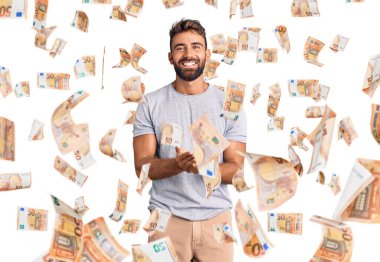 Elleri avuçlarında gülümseyen ya da el hareketi yapan gündelik kıyafetler giyen İspanyol genç bir adam. Bekleme ve koruma