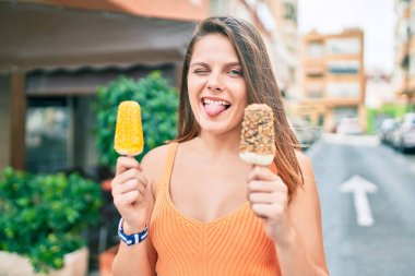 Genç ortadoğulu kız dil ısırıyor ve şehirde dondurma tutuyor..