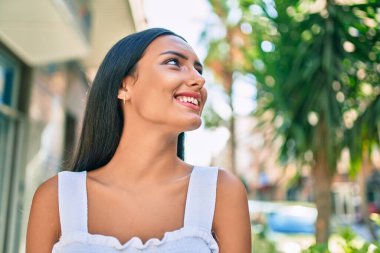 Genç Latin kız gülümsüyor. Şehrin caddesinde mutlu bir şekilde yürüyor..