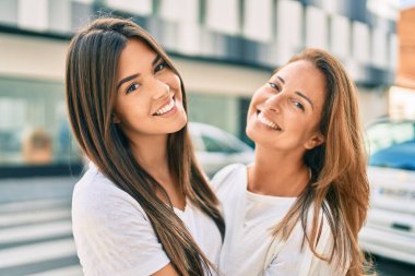 Güzel İspanyol anne ve kızı gülümseyerek şehirde mutlu mesut duruyorlar..