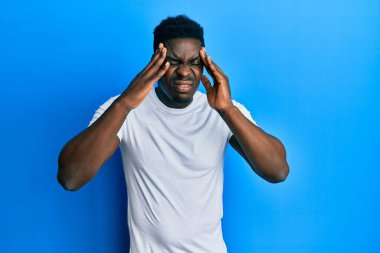 Yakışıklı, beyaz tişörtlü, elleri başının üstünde, stresten baş ağrısı çeken bir zenci. migren ağrısı. 