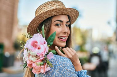 Şehirde çiçekleri tutan yaz şapkası takan genç İspanyol kadın..