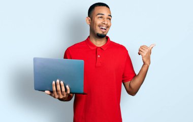 Genç Afro-Amerikalı bir adam bilgisayar laptopuyla çalışıyor. Parmağını kaldırıyor ve ağzı açık gülümsüyor. 