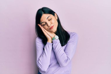 Latin kökenli genç bir kadın gündelik kıyafetler giyip uyuyordu. Yorgun düşler görüyordu. Elleriyle poz veriyordu.. 