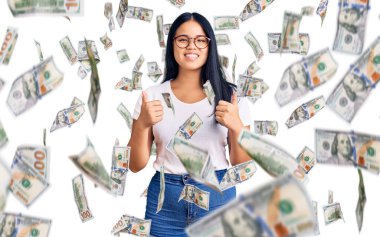 Genç, güzel Asyalı kız, günlük kıyafetler ve gözlük takıyor, başarı işareti yapıyor, elleriyle olumlu jest yapıyor, gülümsüyor ve mutlu. Neşeli ifade ve kazanan jest.