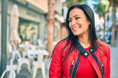 Genç Latin kadın gülümseyerek şehirde mutlu mesut yürüyor..