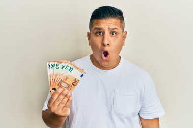 Elinde 50 avroluk banknotlar tutan genç latin adam ağzı açık kalmış, korkmuş ve hayrete düşmüştü. 