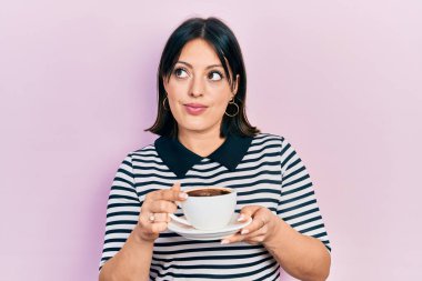 Genç İspanyol kadın bir fincan kahve içiyor gülümsüyor yan tarafa bakıyor ve düşünüyor.. 