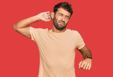 Sakallı, rahat, yorgun, uykulu ve sabahları esnemekte olan rahat tişörtlü yakışıklı bir genç. 