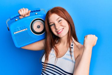 Genç kızıl saçlı kız radyoda bağırıyor gururla, zaferi kutluyor ve başarıyı kollarını kaldırarak kutluyor. 