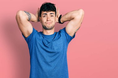 Gündelik tişört giyen genç İspanyol bir adam avuçlarıyla tavşan kulağı hareketi yapıyor alaycı ve şüpheci görünüyor. Paskalya tavşanı konsepti. 