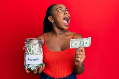 Genç Afro-Amerikalı bir kadın elinde kavanozla elinde 1 dolarlık banknot kızgın ve kızgın bir şekilde bağırıyor öfkeyle yukarı bakıyor.. 