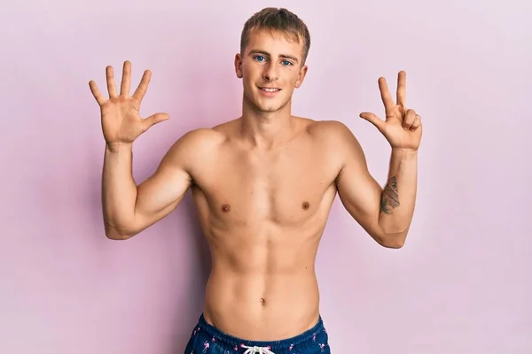 Młody Biały Mężczyzna Strojach Kąpielowych Pokazuje Wskazuje Palcami Numer Osiem — Zdjęcie stockowe