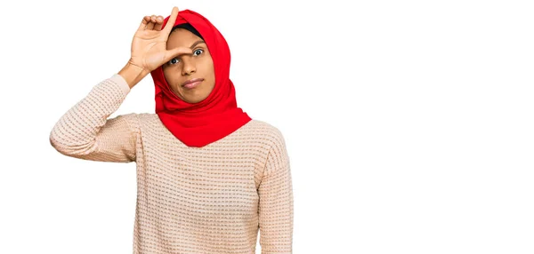 若いですアフリカ系アメリカ人女性身に着けています伝統的なイスラムヒジャーブスカーフ作り楽しいです人々とともに指で額を行います負け犬のジェスチャーモックと侮辱 — ストック写真