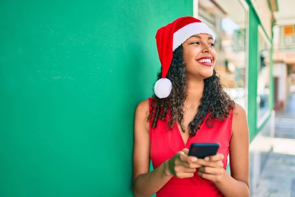 Jovem Afro Americana Usando Chapéu Natal Usando Smartphone Encostado Parede — Fotografia de Stock