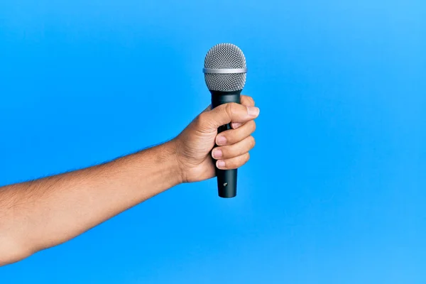 Mano Del Hombre Hispano Sosteniendo Micrófono Sobre Fondo Azul Aislado — Foto de Stock