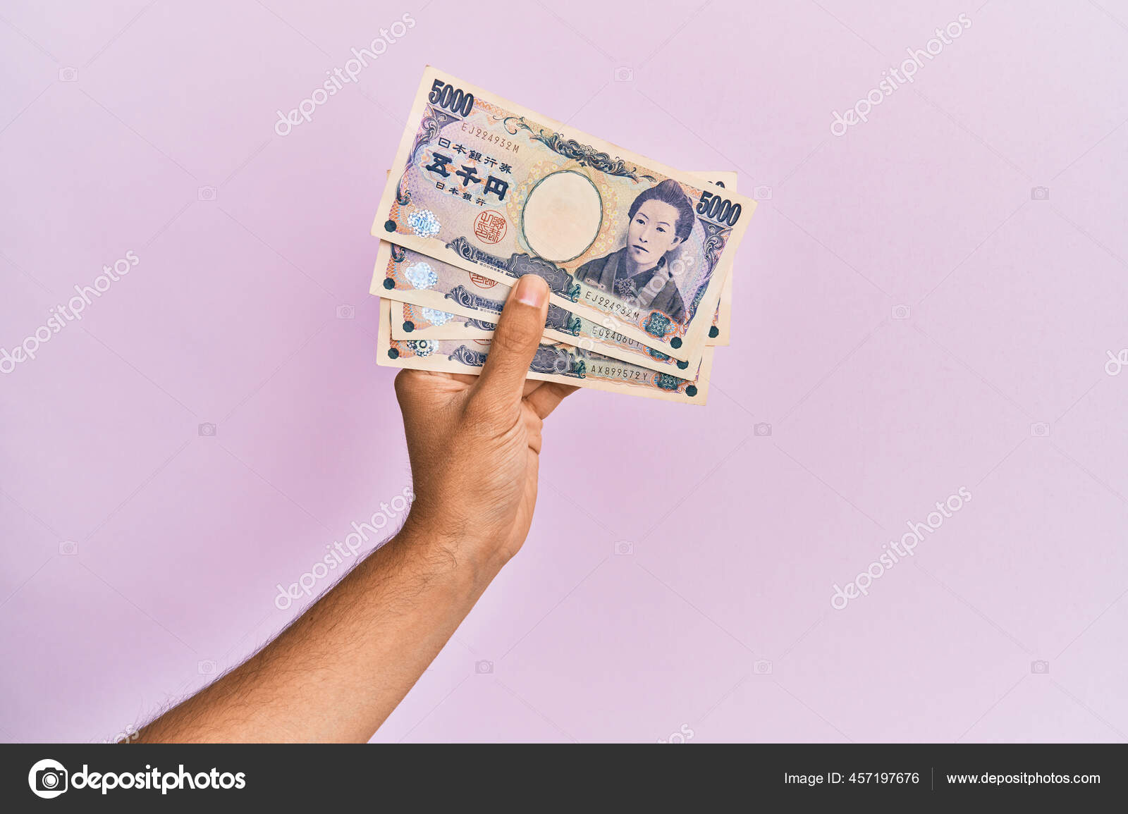 西班牙手拿着5000日元的钞票背景是粉红色的——图库图片© Krakenimages.com #457197676