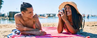 Genç Latin çift plajda klasik kamera kullanarak fotoğraf çekiyor..