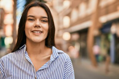 Genç İspanyol kız gülümseyerek şehirde mutlu mesut dikiliyor..