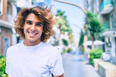 Genç, yakışıklı, gülümseyen bir İspanyol. Şehrin caddesinde mutlu bir şekilde yürüyor.